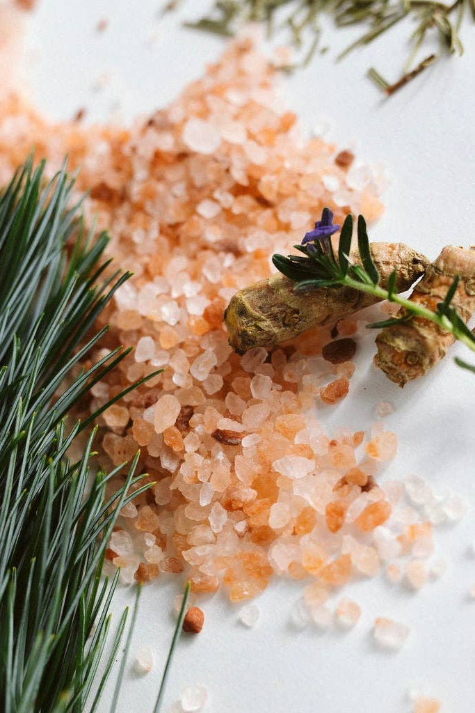 Pink himalayan salt with herbs and flowers on a white background