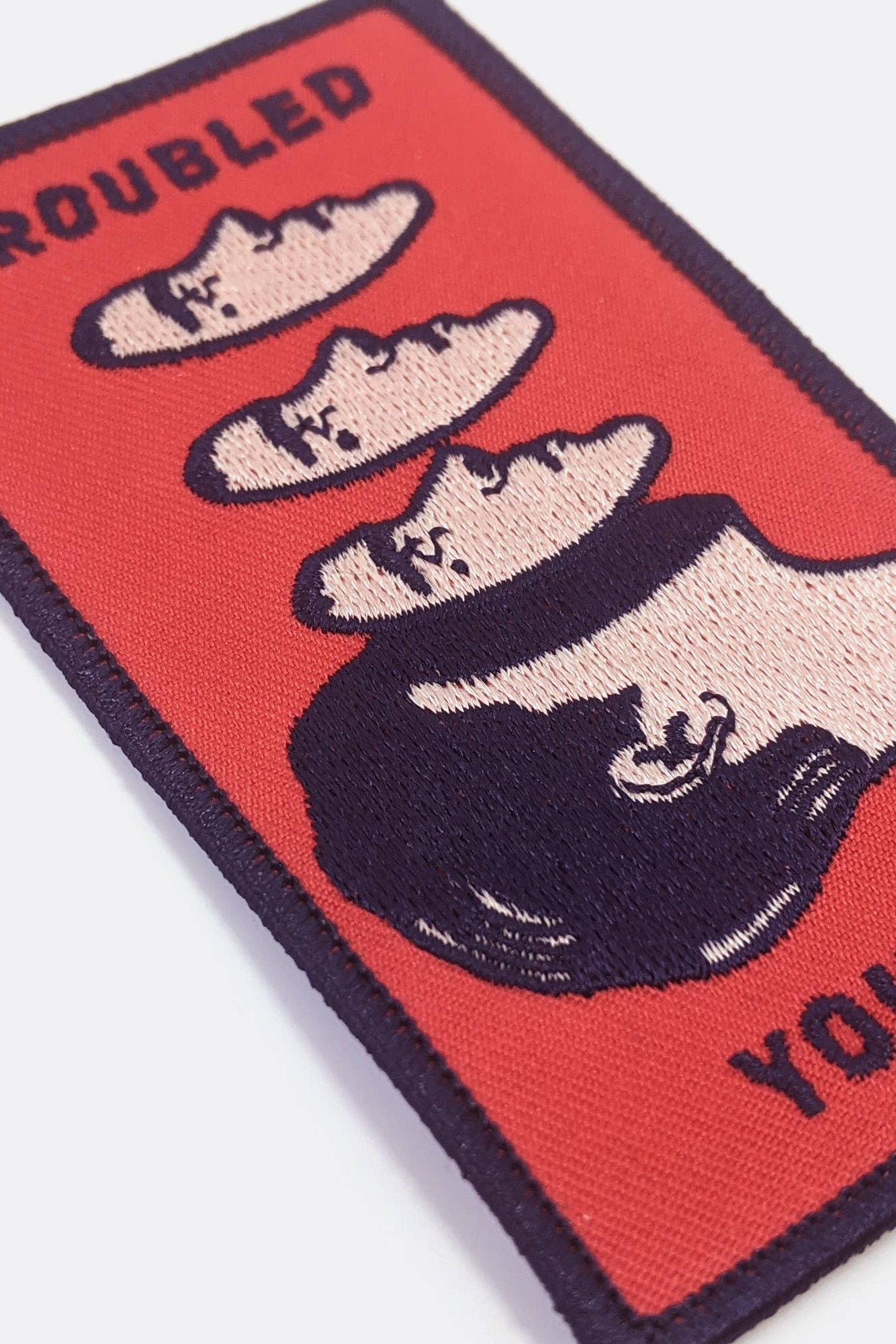 Embroidered Badaboöm Studio patch with 'Troubled Youth' text and graphic design on a red background