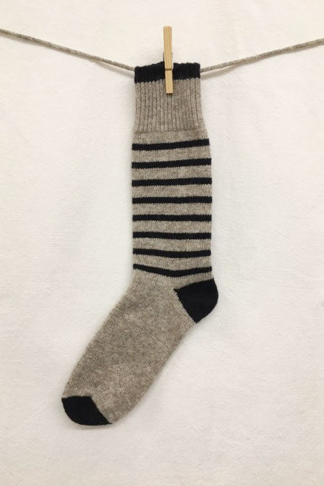 Knitted Socks by Charlevoix Pure Laine in Grey/Navy
stripe are shown hanging on a clothesline against a white background