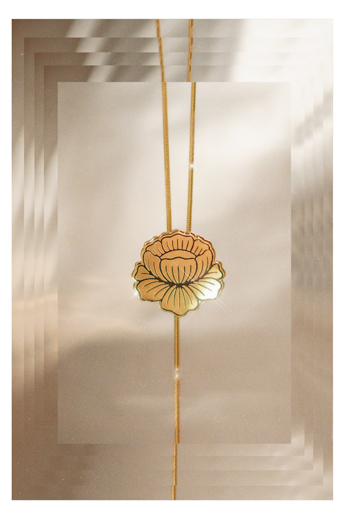The FLEUR DORÉE Flower Bolo Tie from Lord Violet, with gold art deco flower on a snake chain, is shown against a translucent background.