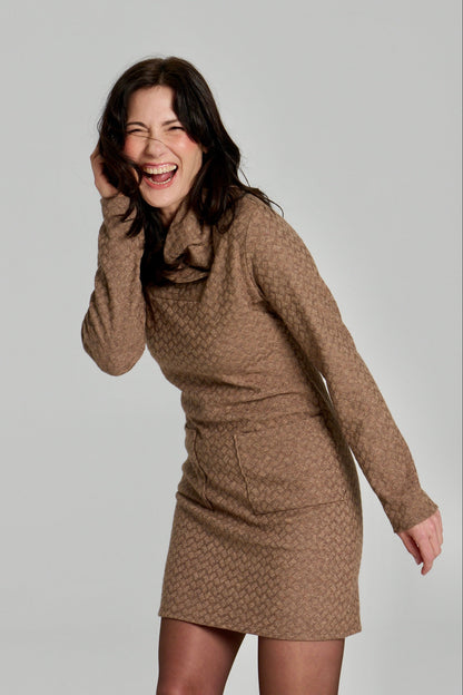 A woman wearing the Sacha Tunic by Kollontai in Brown, a textured knit straight cut tunic with a funnel collar and large patch pockets. She is standing in front fo a white background. 