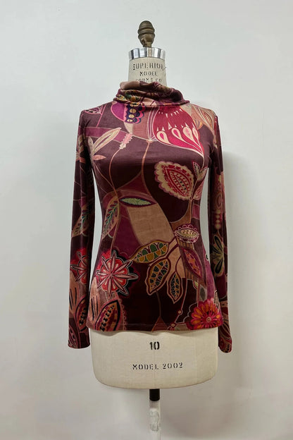 The Everdeen Top by Kollontai, featuring a turtleneck, long sleeves and a purple print, is shown a mannequin.