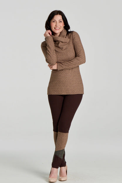 A woman wearing the Eloi Sweater by Kollontai in Brown, a slim fitting textured sweater with a large crossover collar. she is wearing it with brown pants and standing in front of a white background. 