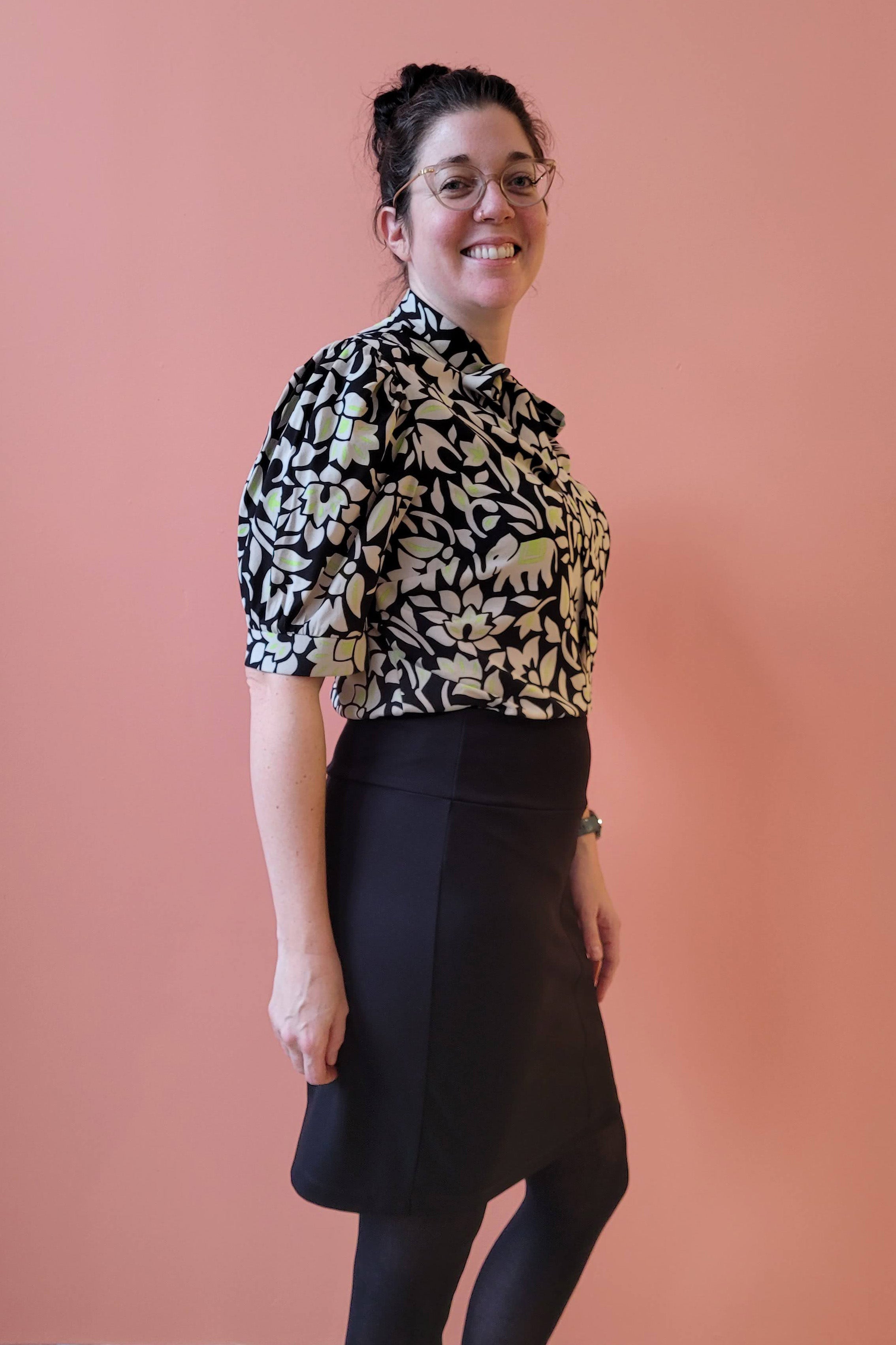 Pema Blouse by Studio D, Green Elephants, side view, black and white pattern with subtle elephants with pops of green, cut out and tie detail at neckline, slightly bloused sleeve with cuff above the elbow, sizes XS to XL ,made in Ottawa