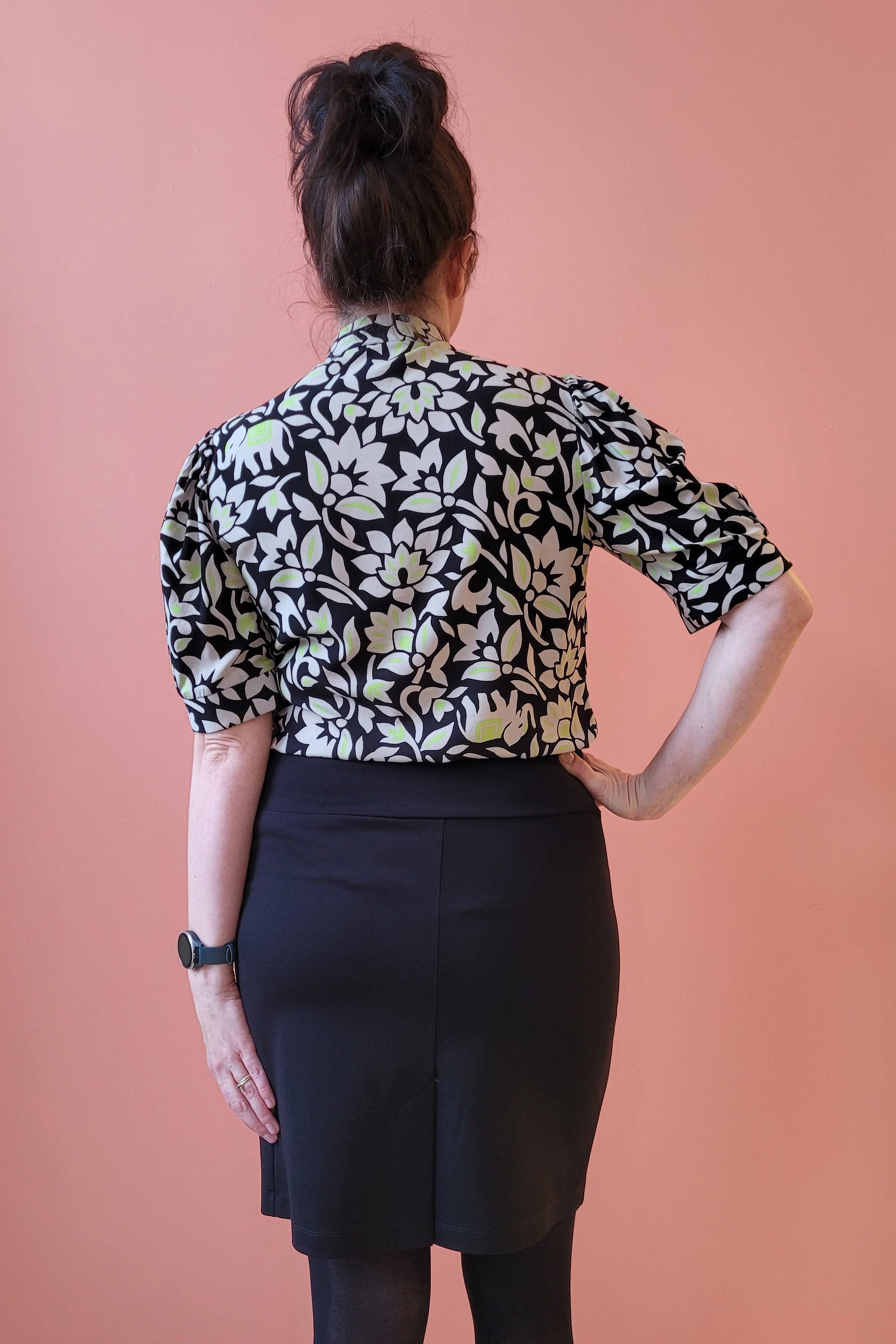 Pema Blouse by Studio D, Green Elephants, back view, black and white pattern with subtle elephants with pops of green, cut out and tie detail at neckline, slightly bloused sleeve with cuff above the elbow, sizes XS to XL ,made in Ottawa