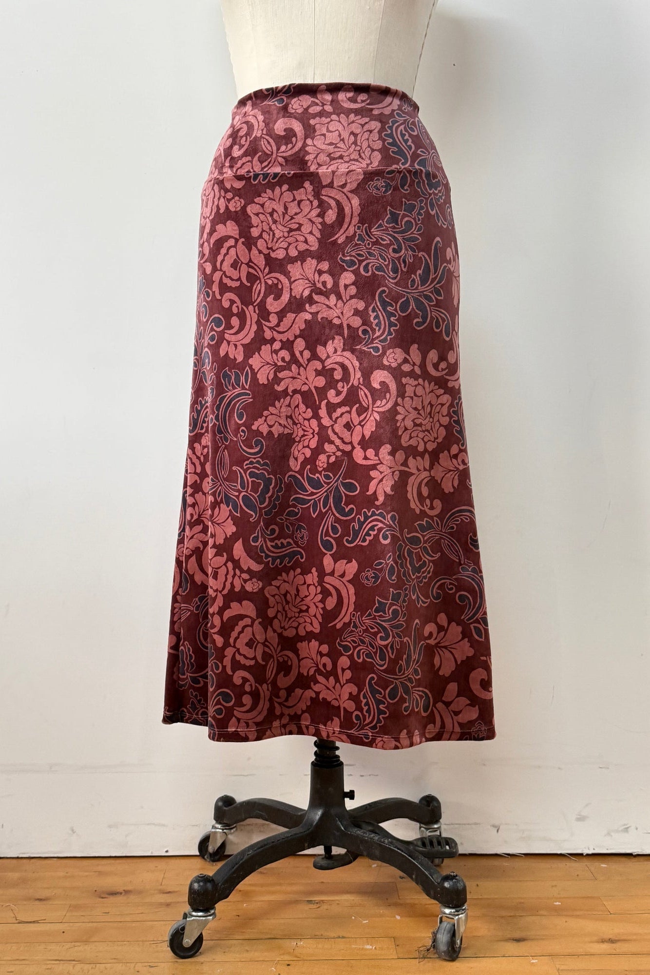 The Kollontai Winslet skirt, a burgundy velvet midi skirt, is shown on a mannequin against a white background. 