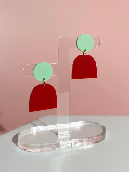 Mint and Red on a clear stand against a pink background