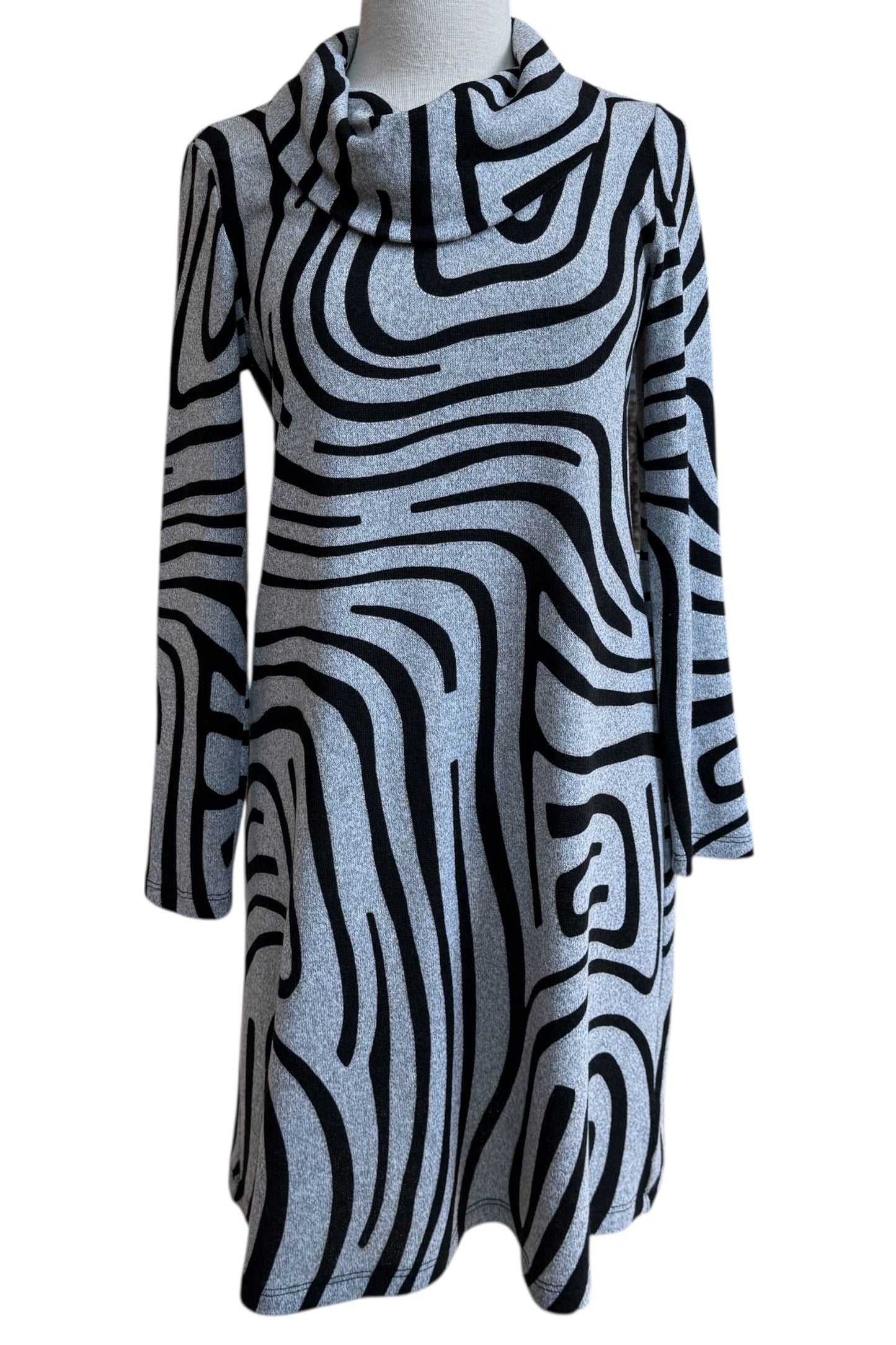 The Powell Dress by Compli K in Black and Silver Swirl, featuring a cowl neck, long sleeves, and a slight trapeze shape, is shown in front of a white background. 