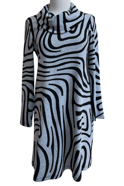 The Powell Dress by Compli K in Black and Silver Swirl, featuring a cowl neck, long sleeves, and a slight trapeze shape, is shown in front of a white background. 