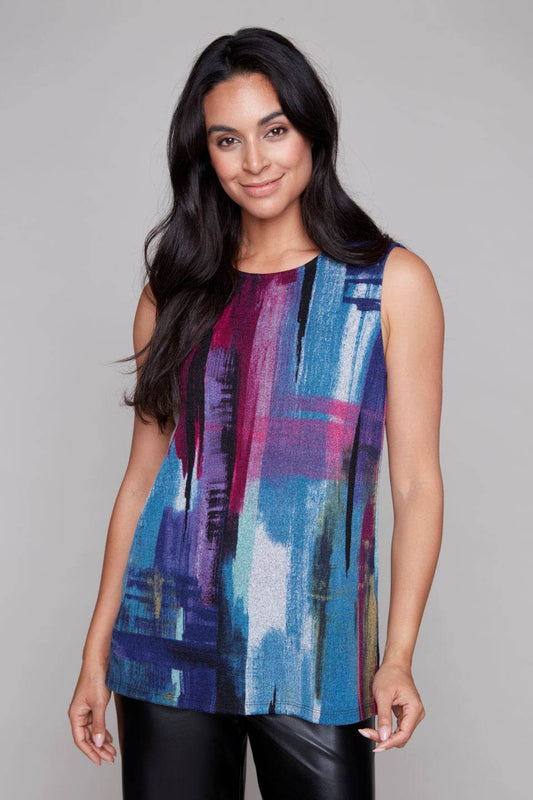 A woman wearing the Preston Top by Compli K in Blue and Berry Abstract print, a long sleeveless top with a round neck. She is wearing it with black pants and standing in front of a grey background. 