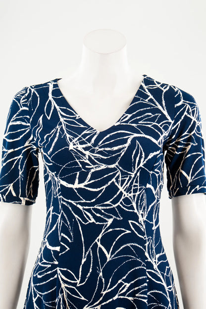 A close up view of the Liana Dress by Karkass in Navy and white print, an above the knee dress with short sleeves, a V-neck and princess seams, is show on a mannequin against a white background. 