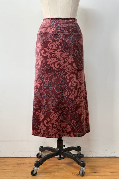 Back view of the Kollontai Winslet skirt, a burgundy velvet midi skirt, is shown on a mannequin against a white background. 