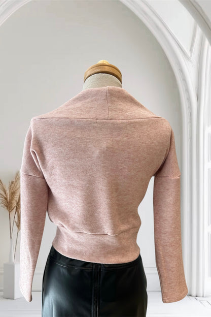 A back view of the Changes Sweater by Allison Wonderland in Pink, featuring a large cowl neck, long dropped sleeves, and a wide waistband, is shown with the Desire Skirt in Black against a white arched backdrop. 