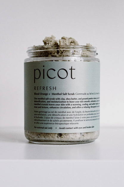 A clear glass jar of Picot Refresh Blend Orange + Menthol Salt Scrub containing textured herbal scrub, set against a plain white background.