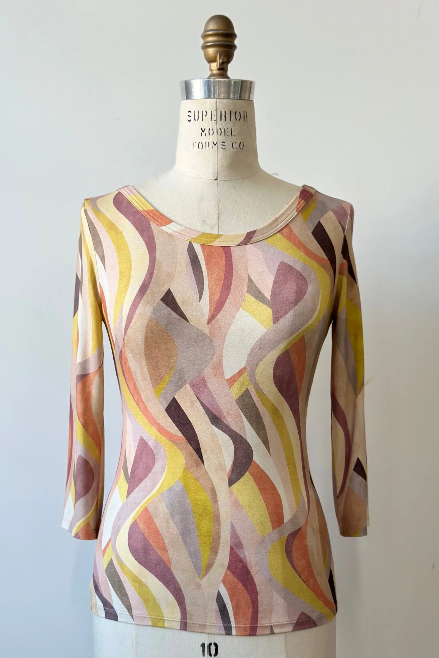 The Vellina Top from Kollontai in Peach print, a 3/4 sleeve fitted top with a wide neck, is shown on a mannequin against a white background. 