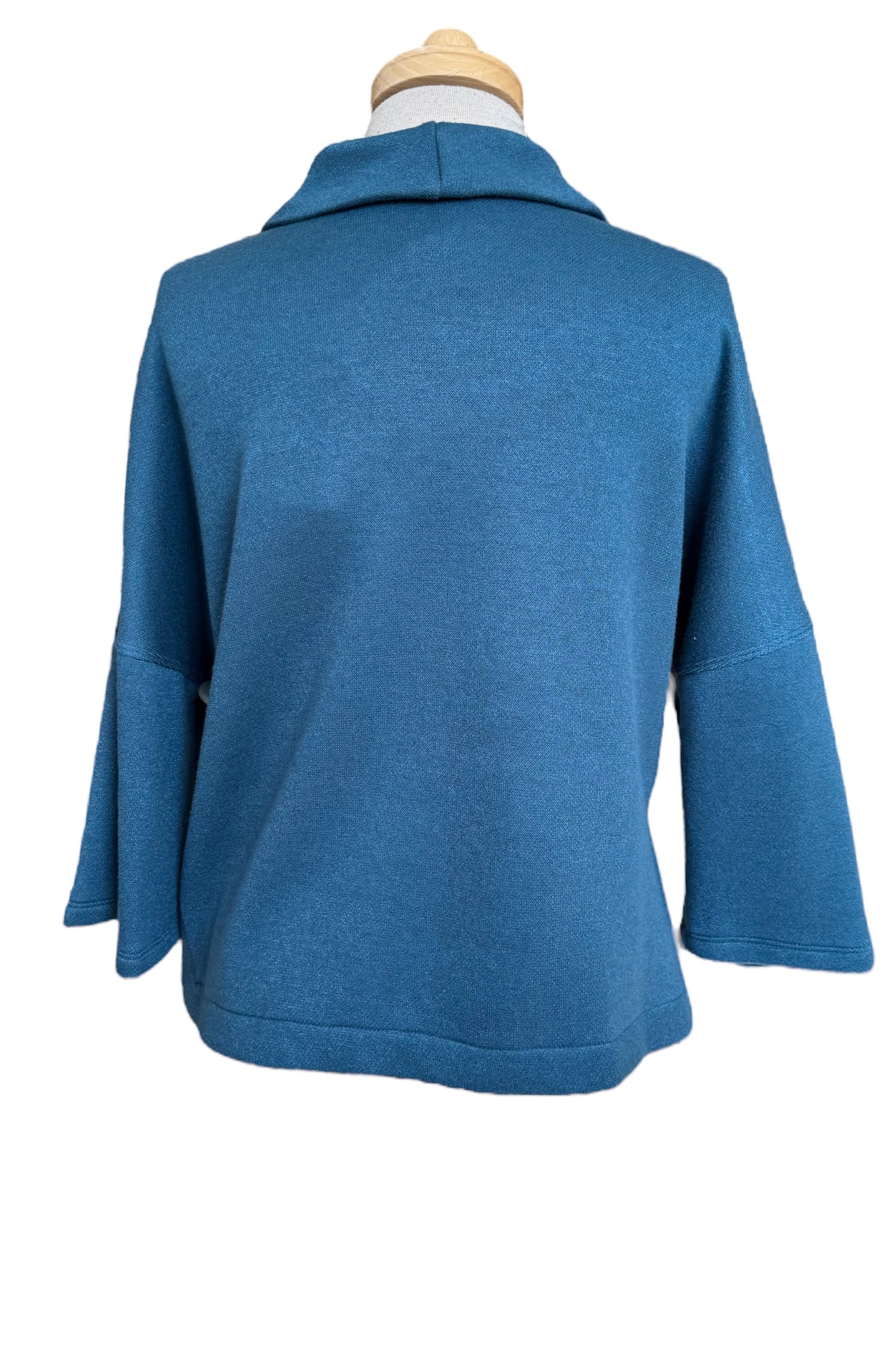 A back view of the Paige Sweater by Compli K in Peacock, featuring a large cowl neck, drop-sleeves, a loose fit, and side slits, is shown on a mannequin against a white background. 