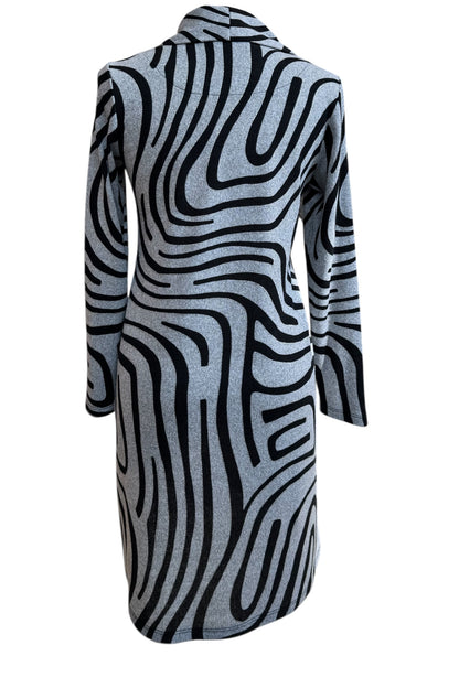 A back view of the Powell Dress by Compli K in Black and Silver Swirl, featuring a cowl neck, long sleeves, and a slight trapeze shape, is shown in front of a white background. 