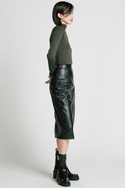 Side view of a woman wearing the Aches Turtleneck by Allison Wonderland in Green, a slim fitting classic turtleneck. She is wearing it with the Desire Skirt in Black and standing in front of a white background. 