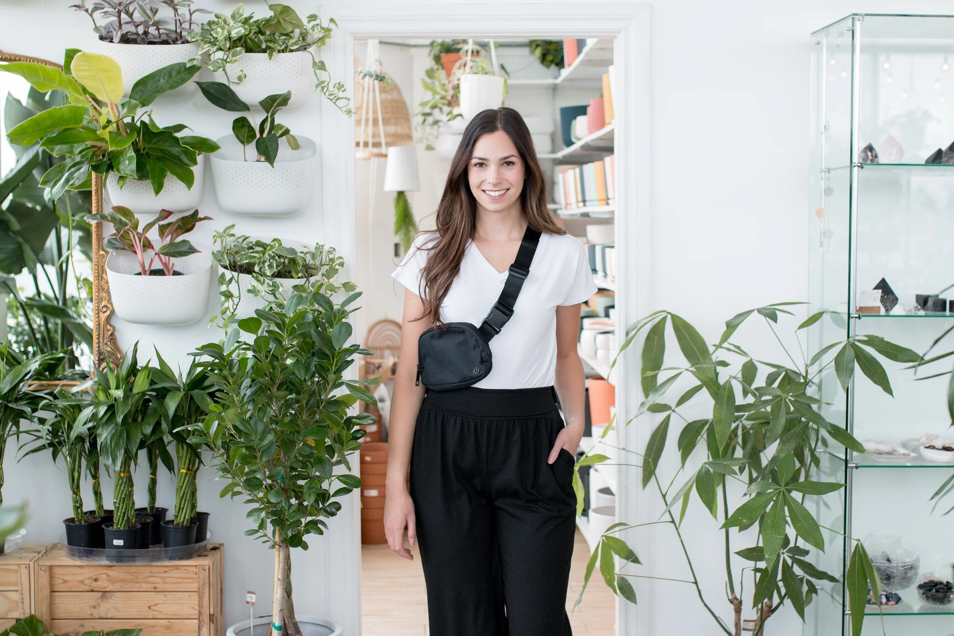 A woman wearing the Bree Wide Leg Pants by Ang Hill in Black, cropped wide-legged pants with a high elastic waist band and deep pockets. She is wearing them with a white t-shirt and standing in a pottery studio. 