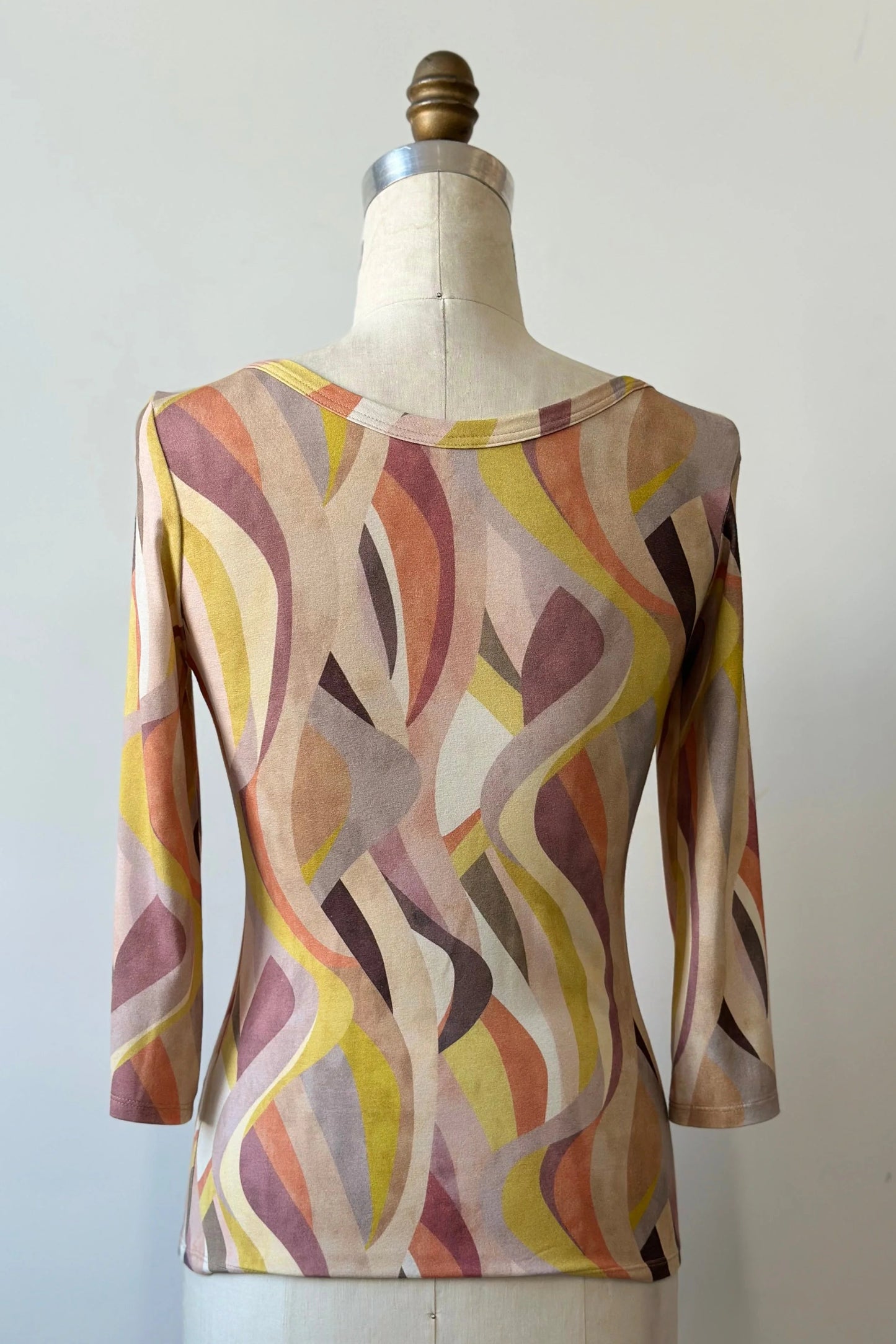 A back view of the Vellina Top from Kollontai in Peach print, a 3/4 sleeve fitted top with a wide neck, is shown on a mannequin against a white background. 