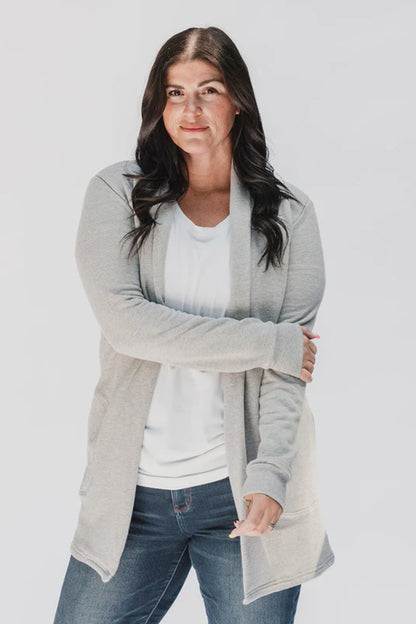 A woman wearing the Classic Briton Cardigan by Blondie Apparel in Grey with jeans and a white t-shirt, standing in front of a white background 