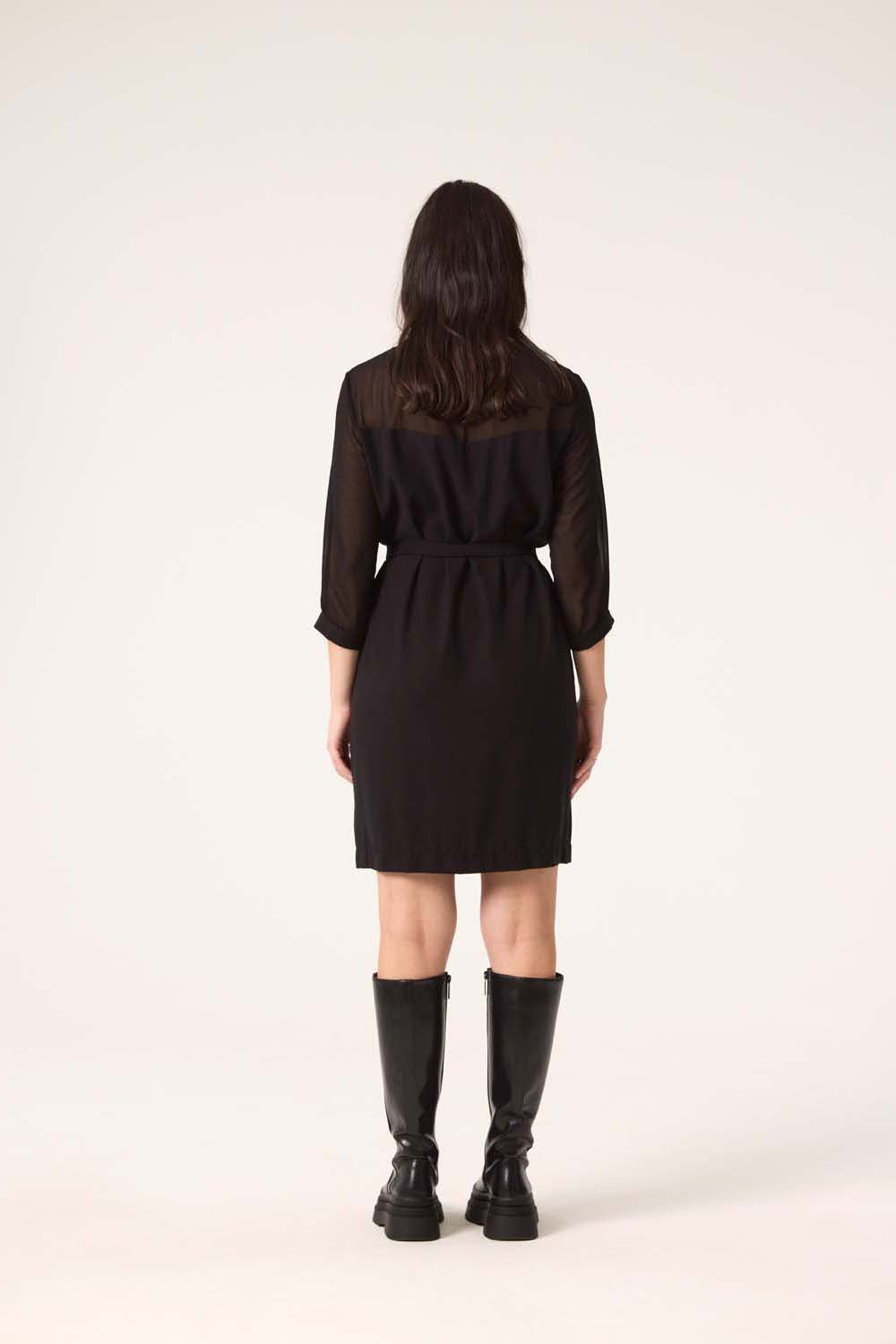 Back view of a woman wearing the Blur Dress by Cokluch in Black, standing in front of a white background