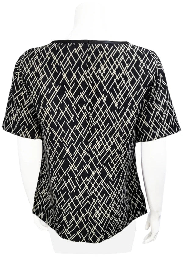 A back view of the Cecil Box Blouse by Mandala in Crosstown print is shown on a mannequin against a white background. It has a high neckline, wide 1/2 sleeves, and a side hem slit detail.