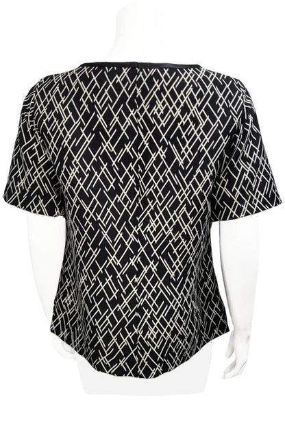 A back view of the Cecil Box Blouse by Mandala in Crosstown print is shown on a mannequin against a white background. It has a high neckline, wide 1/2 sleeves, and a side hem slit detail.