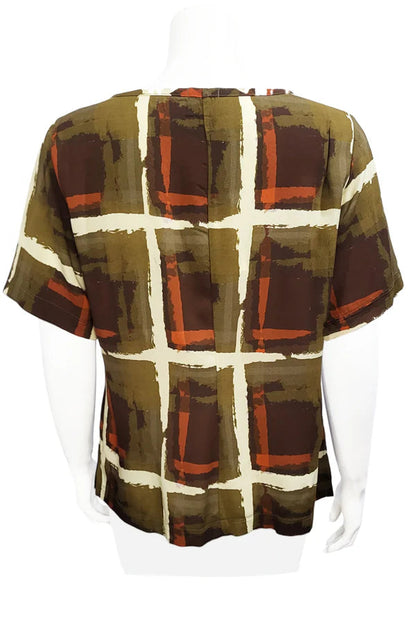 A back view of the Cecil Box Blouse by Mandala in Cubist print is shown on a mannequin against a white background. It has a high neckline, wide 1/2 sleeves, and a side hem slit detail.