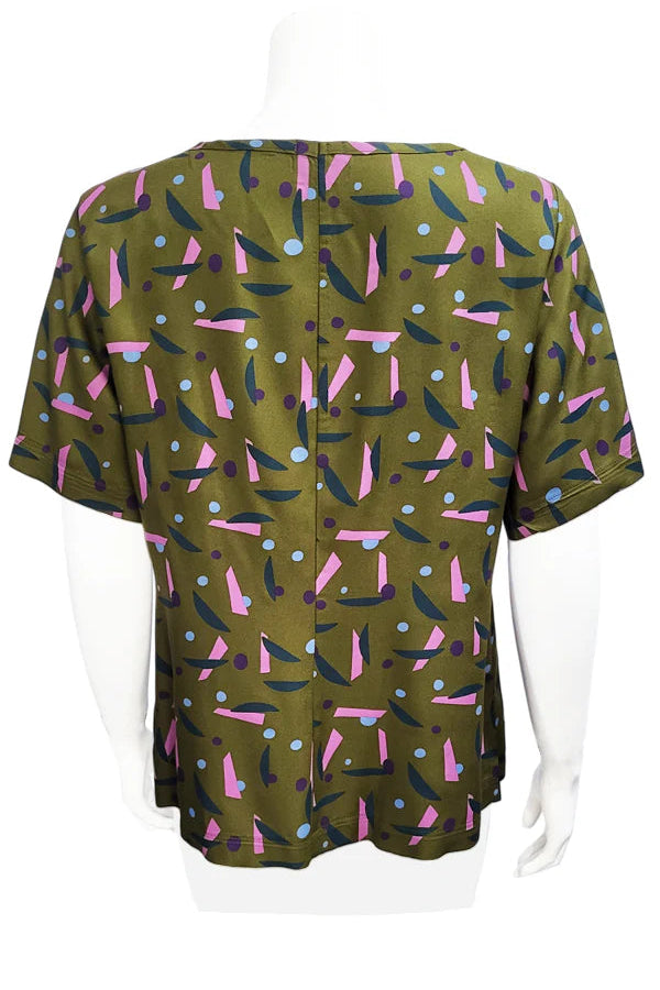 A back view of the Cecil Box Blouse by Mandala in Playtime Ivy print is shown on a mannequin against a white background. It has a high neckline, wide 1/2 sleeves, and a side hem slit detail.