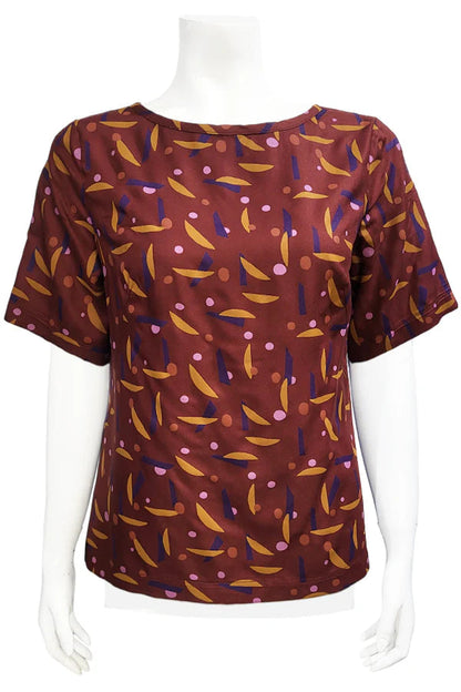 The Cecil Box Blouse by Mandala in Playtime Rust print is shown on a mannequin against a white background. It has a high neckline, wide 1/2 sleeves, and a side hem slit detail. 
