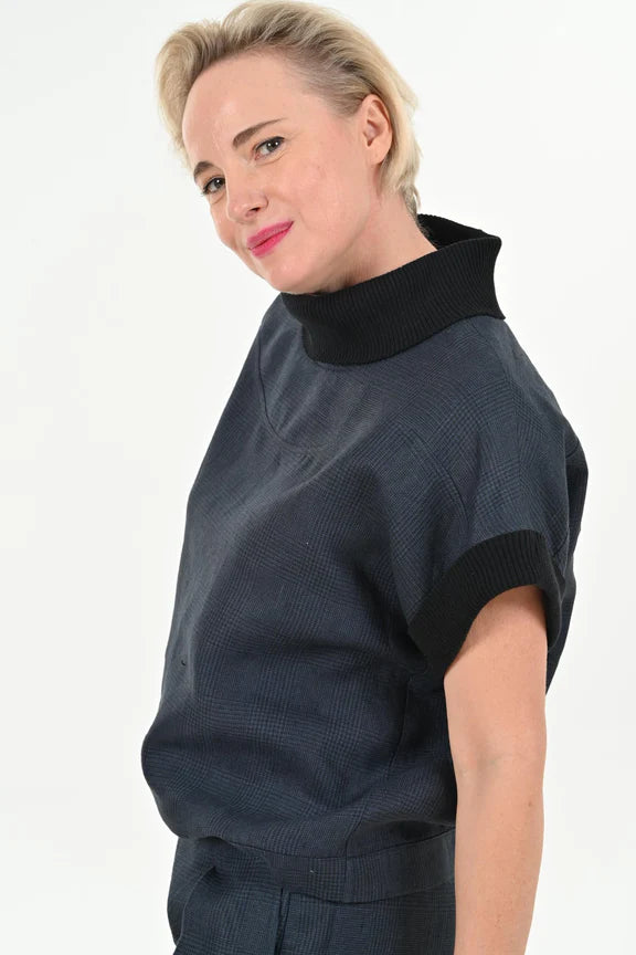 Side waist-up view of a woman wearing the Cleo Top by Julei Design in Navy, standing in front of a white background 