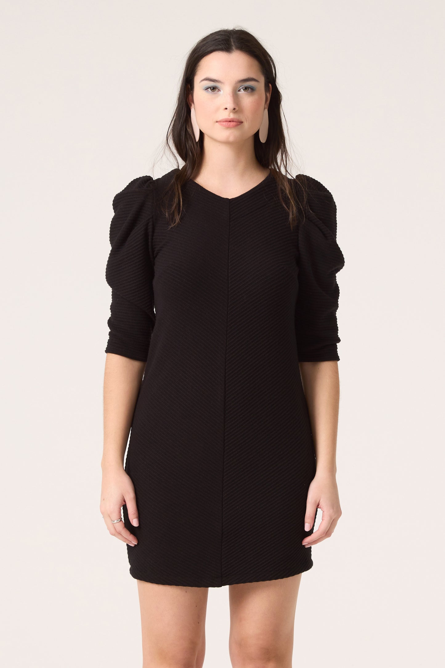 3/4 shot of a woman wearing the Celeste Dress by Cokluch in Black, standing in front of a white background