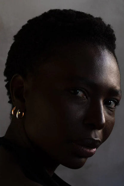 Close up of a woman wearing the Claudine Moncion Stack03 hoop earrings in sterling silver and copper. 