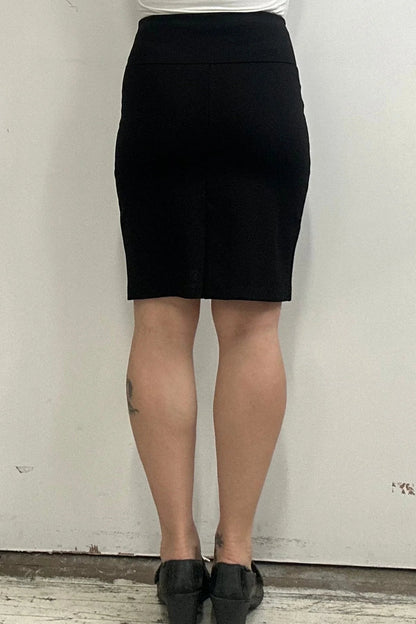 Waist down back view of a woman wearing the Veneto Skirt by Kollontai in Black, a pencil skirt with a wide-pull on waistband that hits above the knee.