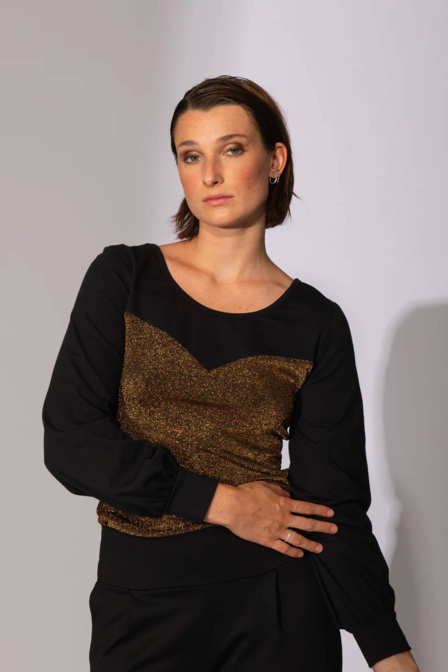 A woman wearing the Spike the Senses Reversible Top by Eve Lavoie in Gold Sparkle, with a sweetheart neckline and puffed sleeves