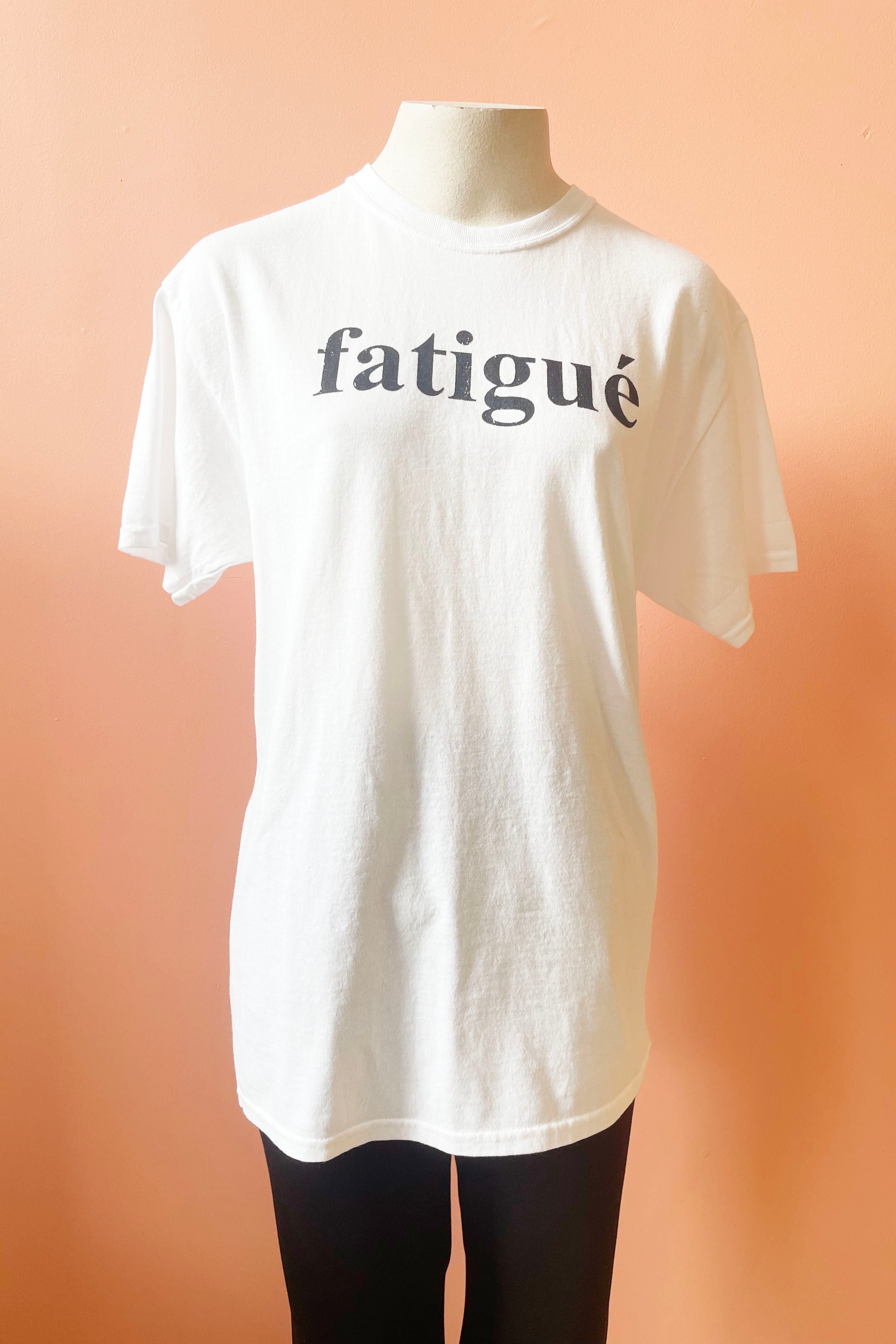 Fatigue Tee by Sara Duke, White, classic t-shirt with the word Fatigue printed on the front, 100% cotton, sizes S to XL, made in Toronto