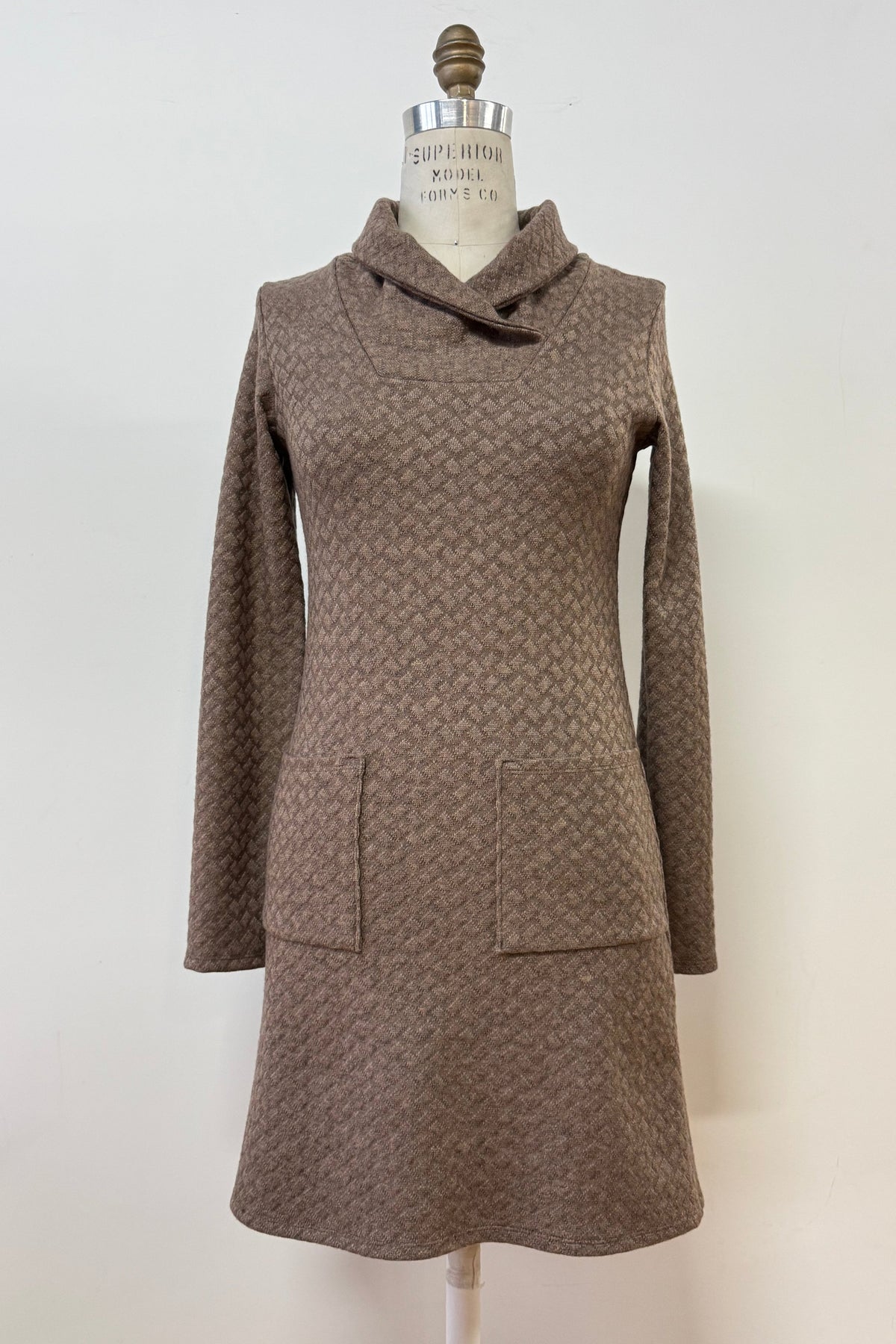 The Sacha Tunic by Kollontai in Brown, a textured knit straight cut tunic with a funnel collar and large patch pockets, is shown on a mannequin against a white background. 