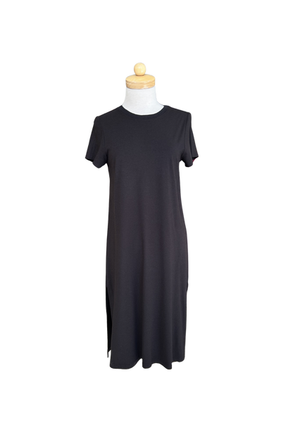 The Frances Midi  by Tangente in Black, a short sleeved loose fitting dress with side slits, is shown on a mannequin against a white background. 