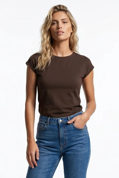 A woman wearing the Eowyn T-Shirt by Kollontai in Chocolate with jeans standing against a grey background. 