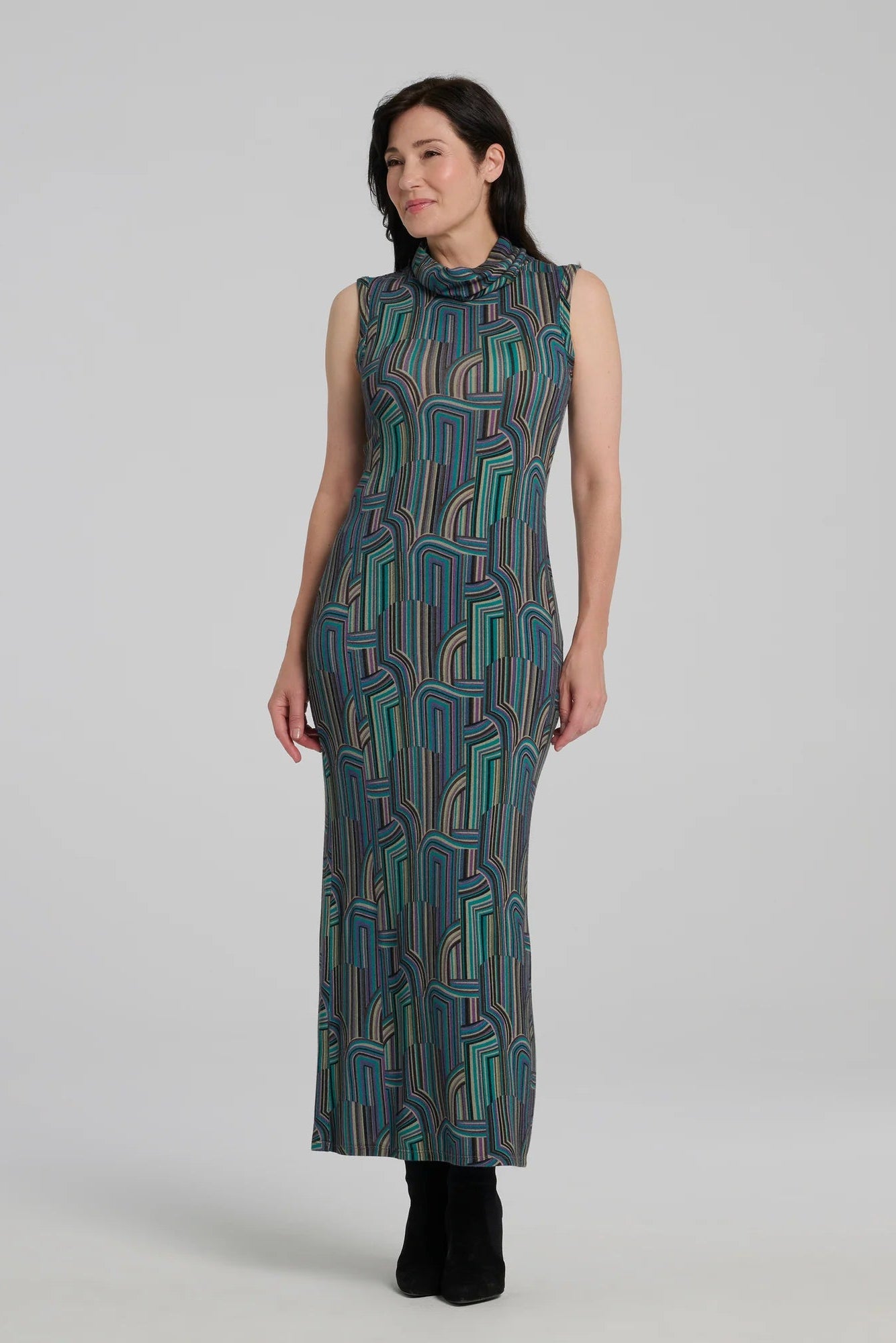 A woman wearing the Ysia Dress by Kollontai, a sleeveless turtleneck dress with a geometric pattern. She is standing in front of a white background. 