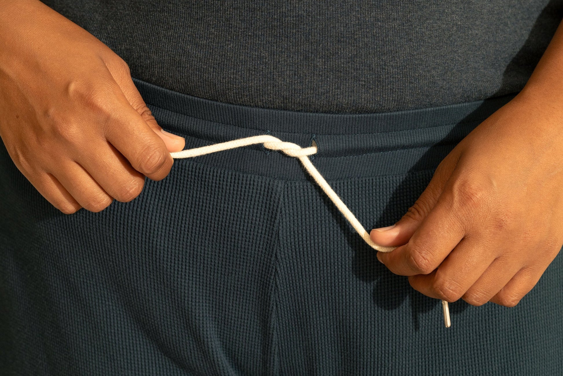 Close up waist and drawstring  detail of a woman wearing the Organic Cotton Lounge Pants from Lights of All in Deep Sea. 