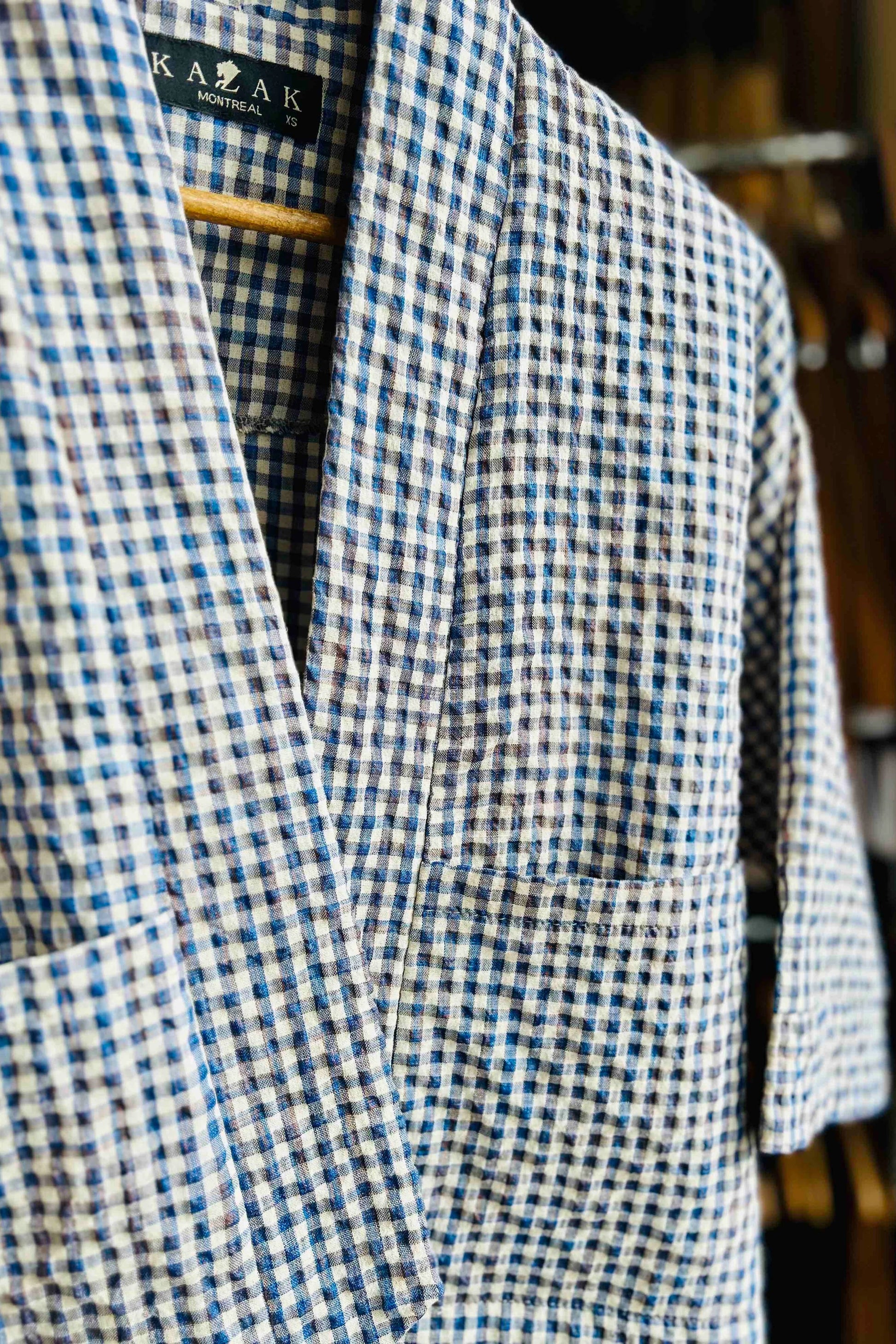 The Magnolia Jacket from Kazak in Sky Vichy/Gingham, a kimono style jacket with 3/4 sleeves and large patch pockets, is shown on a hanger.