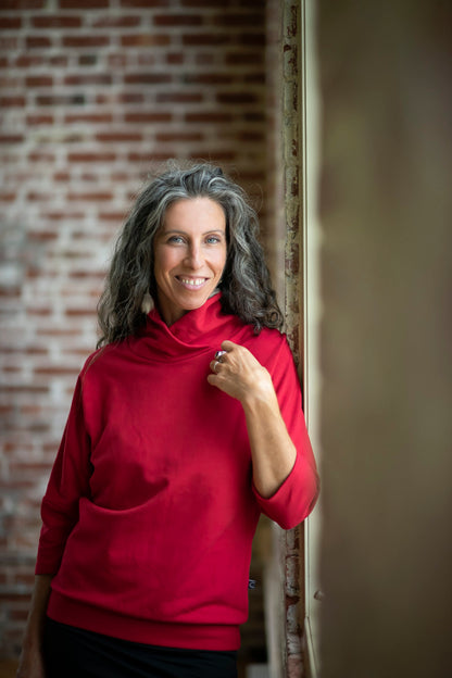 A woman wearing the Beaaa Top by Marie C in Red, standing in front of a brick wall 