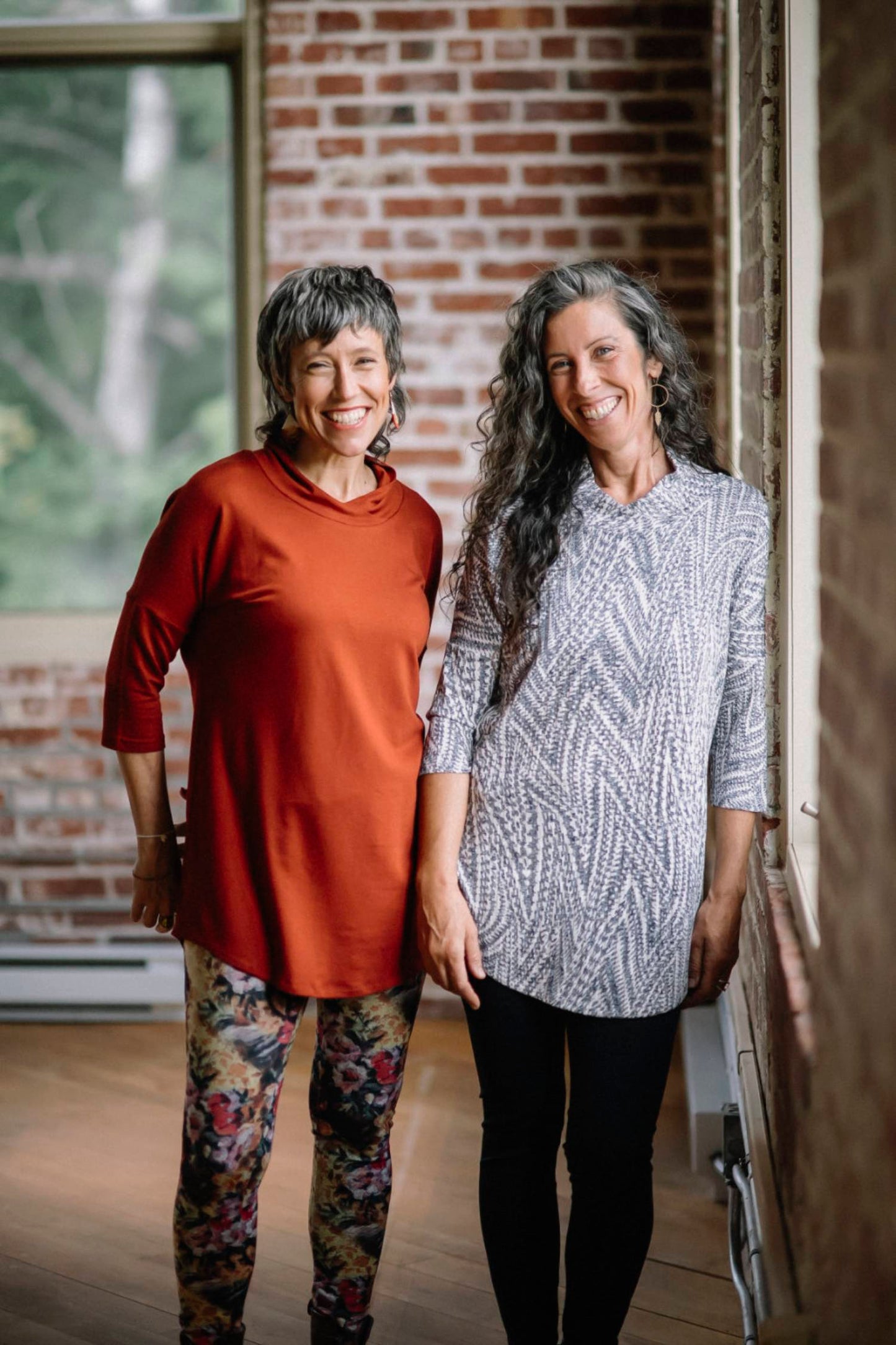 A woman wearing the Juliana Tunic by Marie C in Navy Print and a woman wearing Juliana Tunic by Marie C in Rust, standing in front of a brick wall 