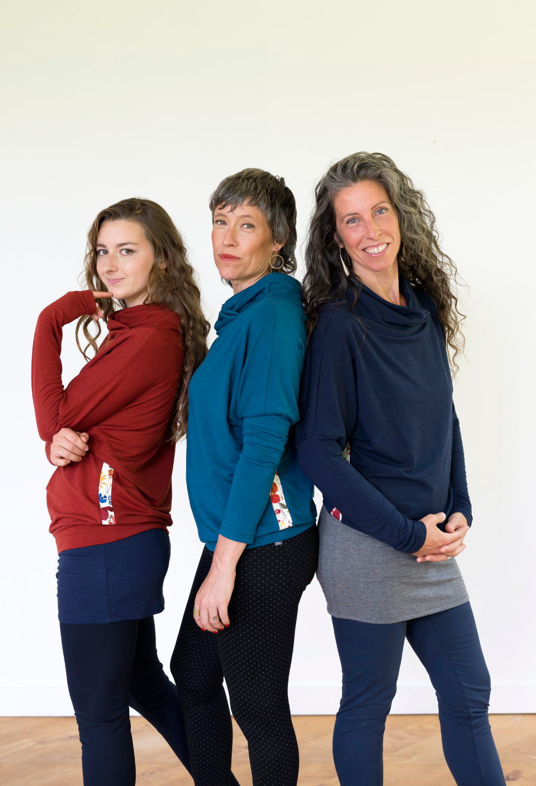 Three women wearing the Mimoso Top by Marie C in Rust, Teal, and Navy, standing in front of a white background 