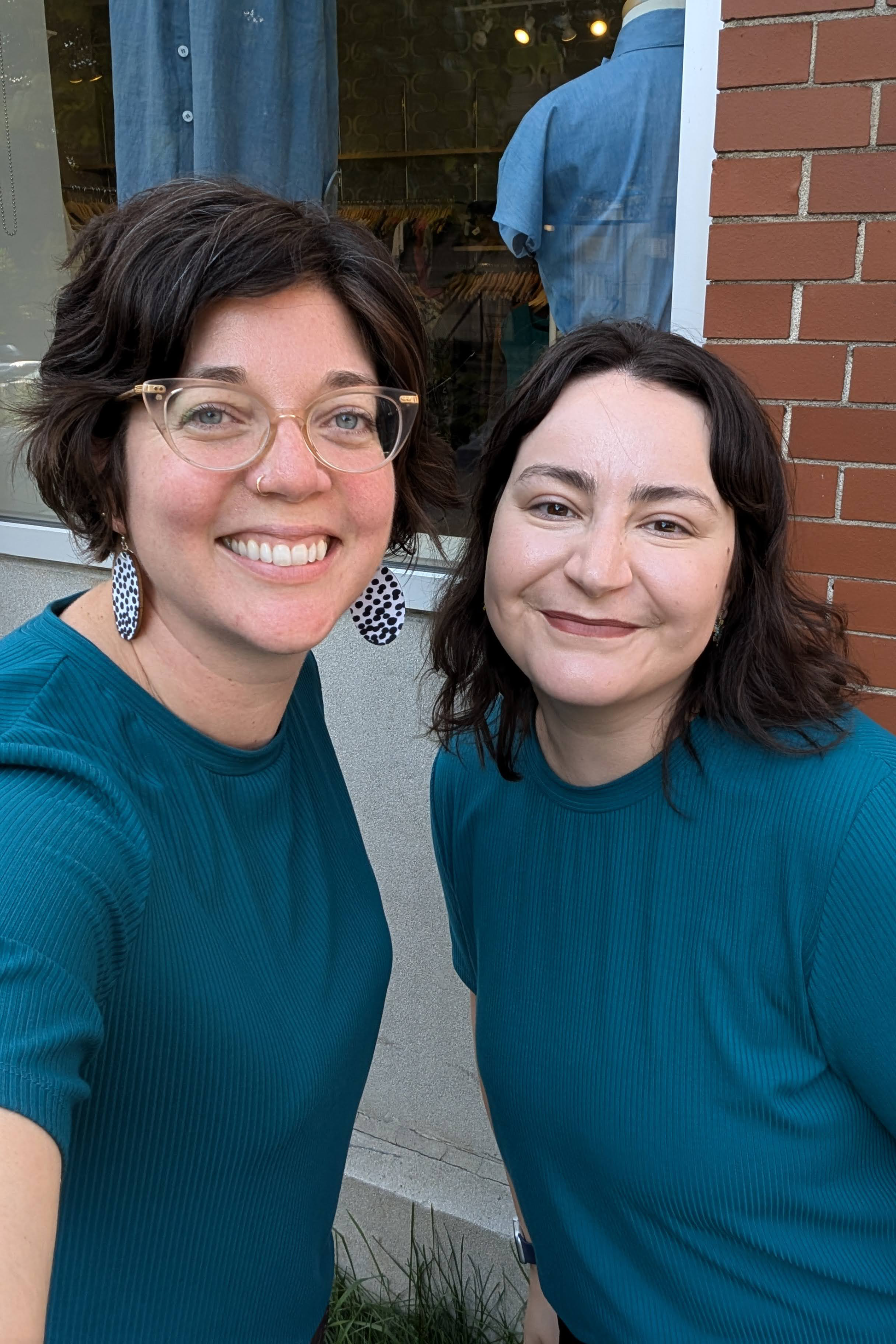 Moira and Val wearing the Flock Exclusive Porto T-shirt by MAS in Teal, standing in front of the window at Flock