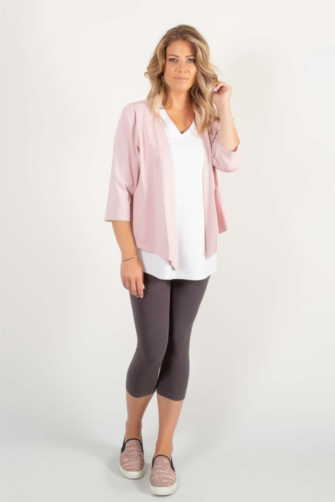 A woman wearing the Charlotte Camisole by Pure Essence in White, standing in front of a white background,