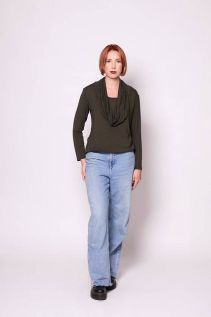 A woman wearing the Lauren Top by Tangente in Spruce with jeans, standing in front of a white background 