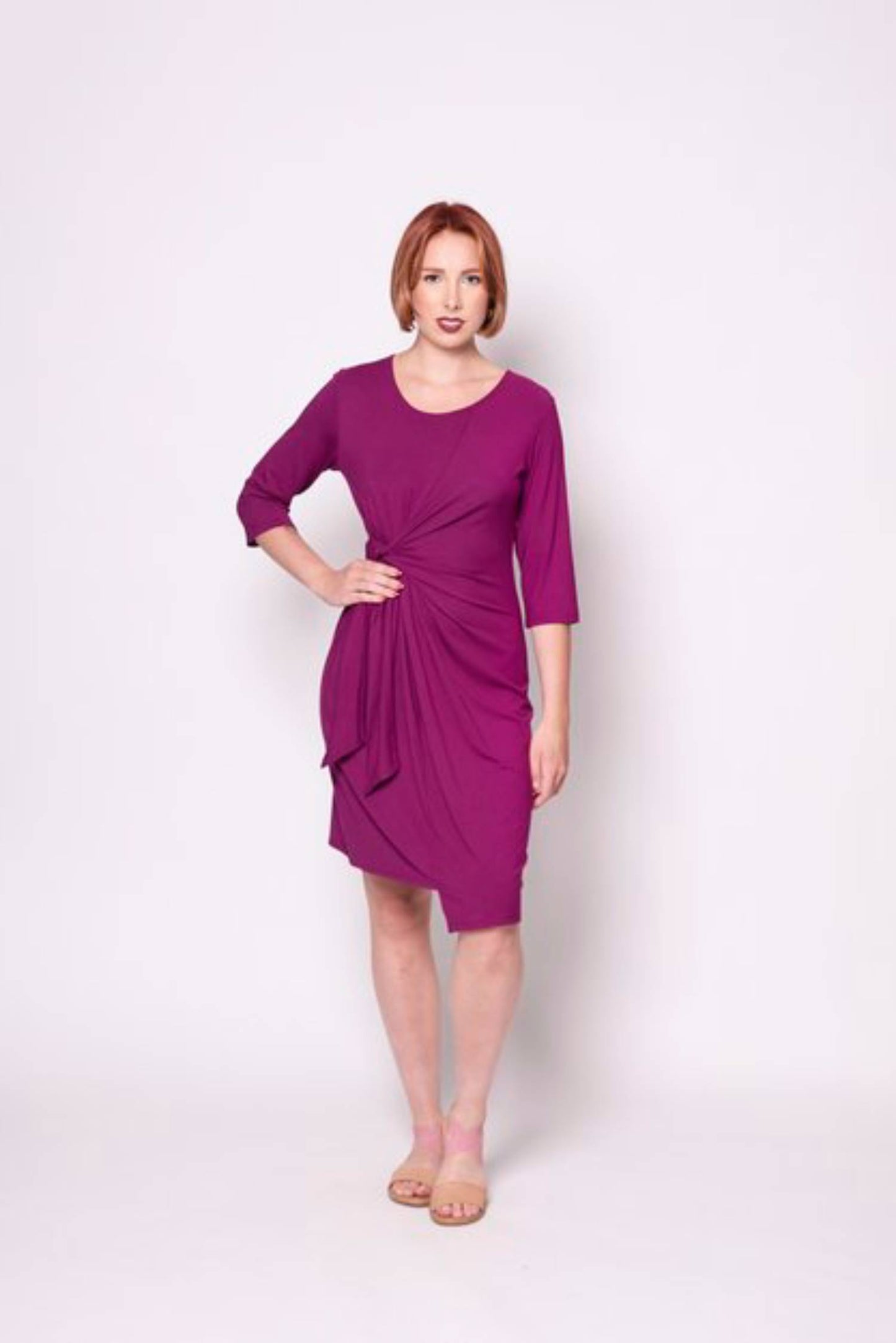 A woman wearing the Mariela Dress by Tangente in Fuschia, standing in front of a white background 